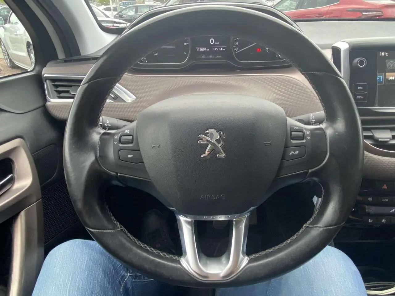 Vue intérieure centrée sur le volant cuir Peugeot 2008 blanc 2015 avec tableau de bord numérique et commandes intégrées.