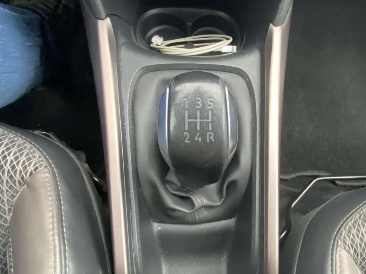 Vue rapprochée du levier de vitesses manuel noir du Peugeot 2008 blanc de 2015, avec console centrale et siège partiel.