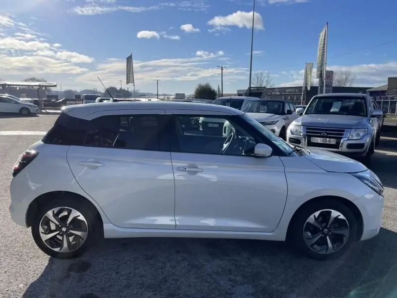 Vue de profil côté gauche d'une Suzuki Swift blanche 2025 avec toit noir et jantes distinctives en alliage.