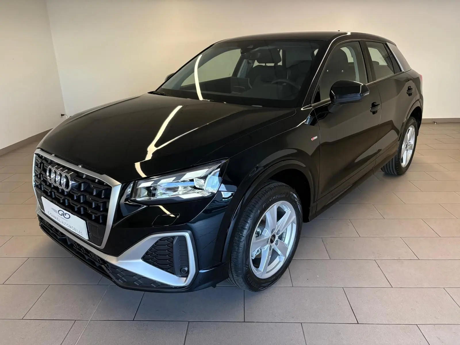 Audi Q2 35 TFSI S line noir mythic en 3/4 avant droit, avec calandre distinctive et jantes argentées.