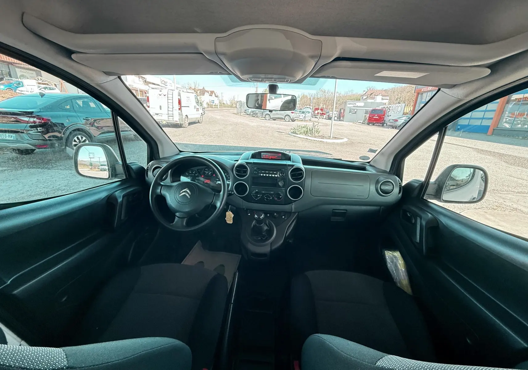 Vue intérieure avant du Citroën Berlingo 2017, montrant le tableau de bord et les sièges en tissu noir.