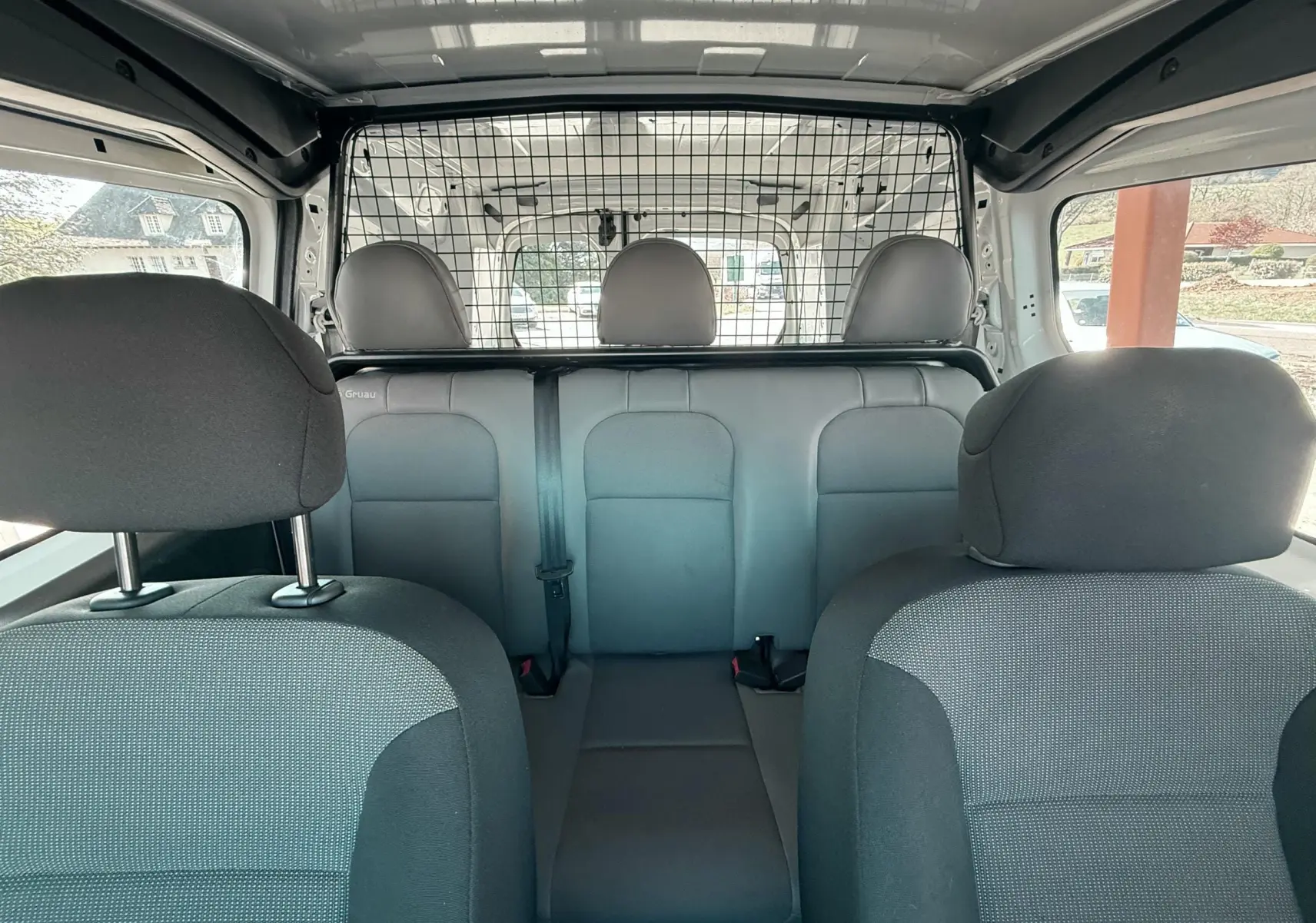 Vue intérieure arrière du Citroën Berlingo 2017, sièges tissu gris et séparation grillagée entre cabine et coffre.