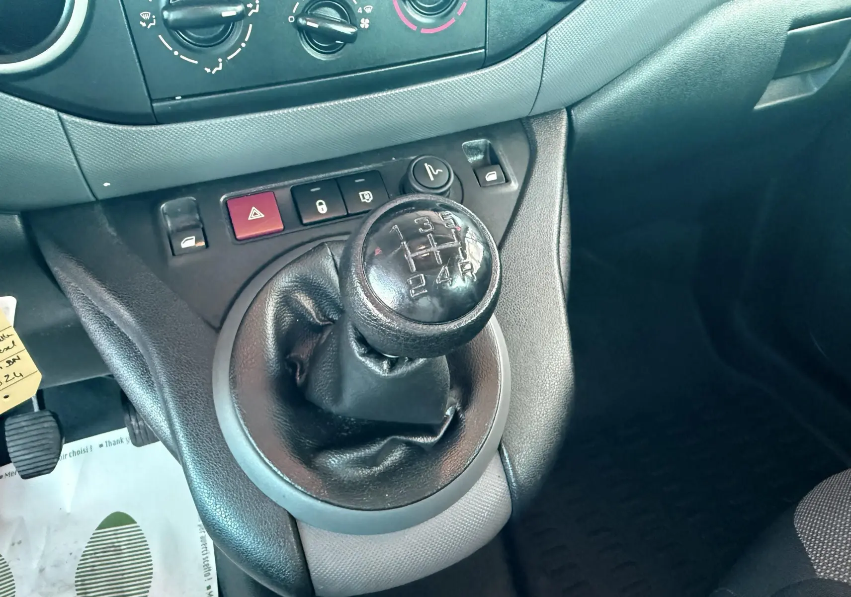 Le levier de vitesses manuel noir de la Citroën Berlingo 2017, avec commandes de climatisation et boutons de sécurité visibles.