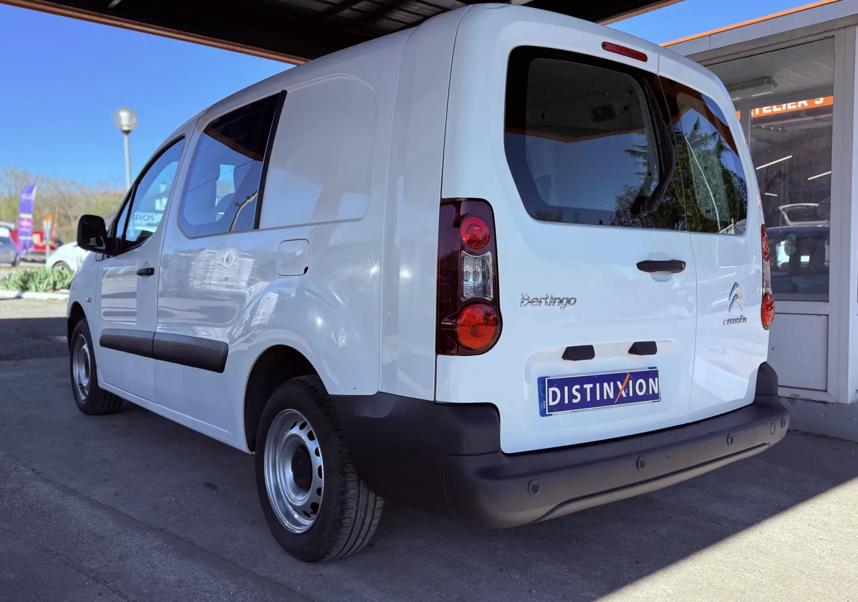 Vue 3/4 arrière droite d’un Citroën Berlingo blanc utilitaire avec vitres teintées et pare-chocs noirs.