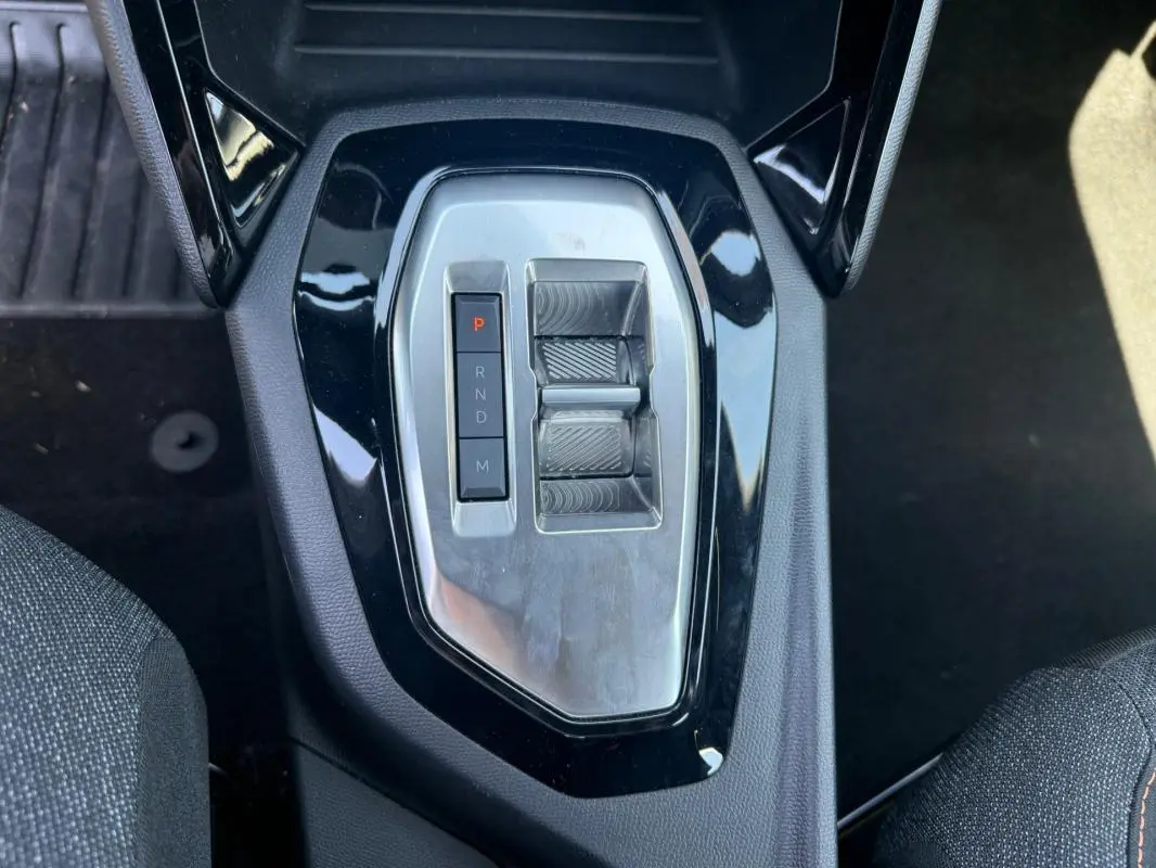 Vue plongeante sur la console centrale du Peugeot 2008 Hybrid noir, montrant la commande de boîte automatique compacte.