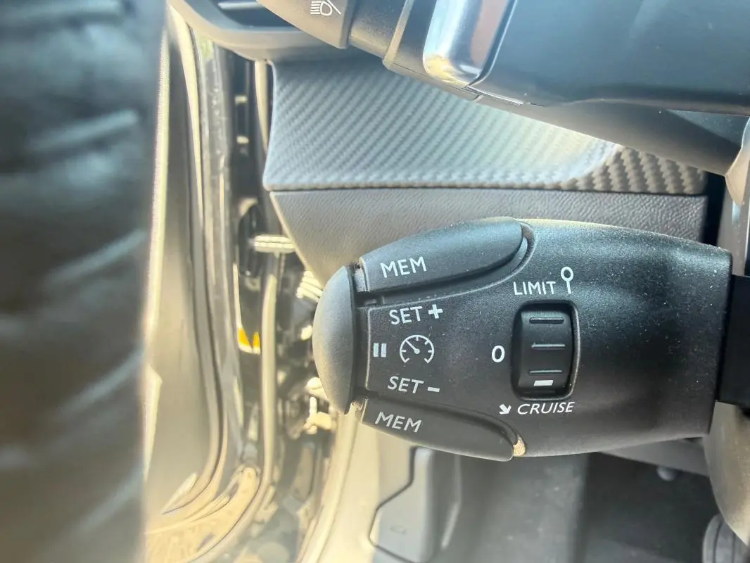 Gros plan sur la commande de régulateur de vitesse du Peugeot 2008 Hybrid 136 e-DCS6 Style noir, intérieur côté gauche.