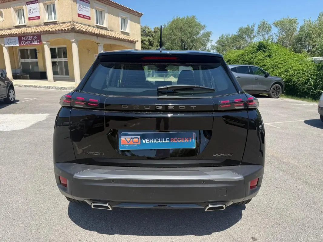 Vue arrière d'un Peugeot 2008 Hybrid noir 2025 avec feux LED caractéristiques et double sortie d'échappement.