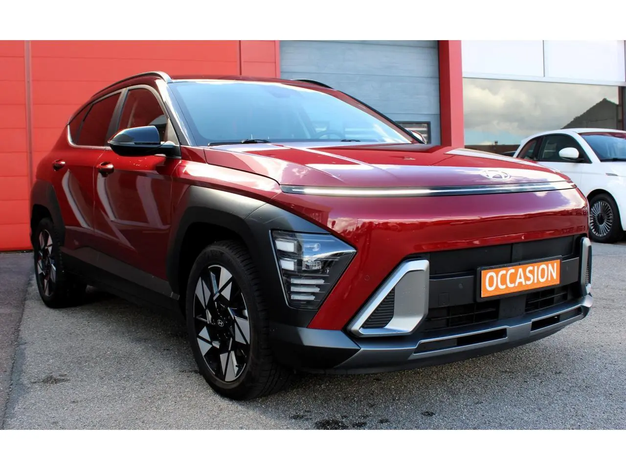 Hyundai Kona 2024 rouge Ultimate Metal avec toit noir, vue 3/4 avant mettant en valeur ses feux LED et jantes alliage.