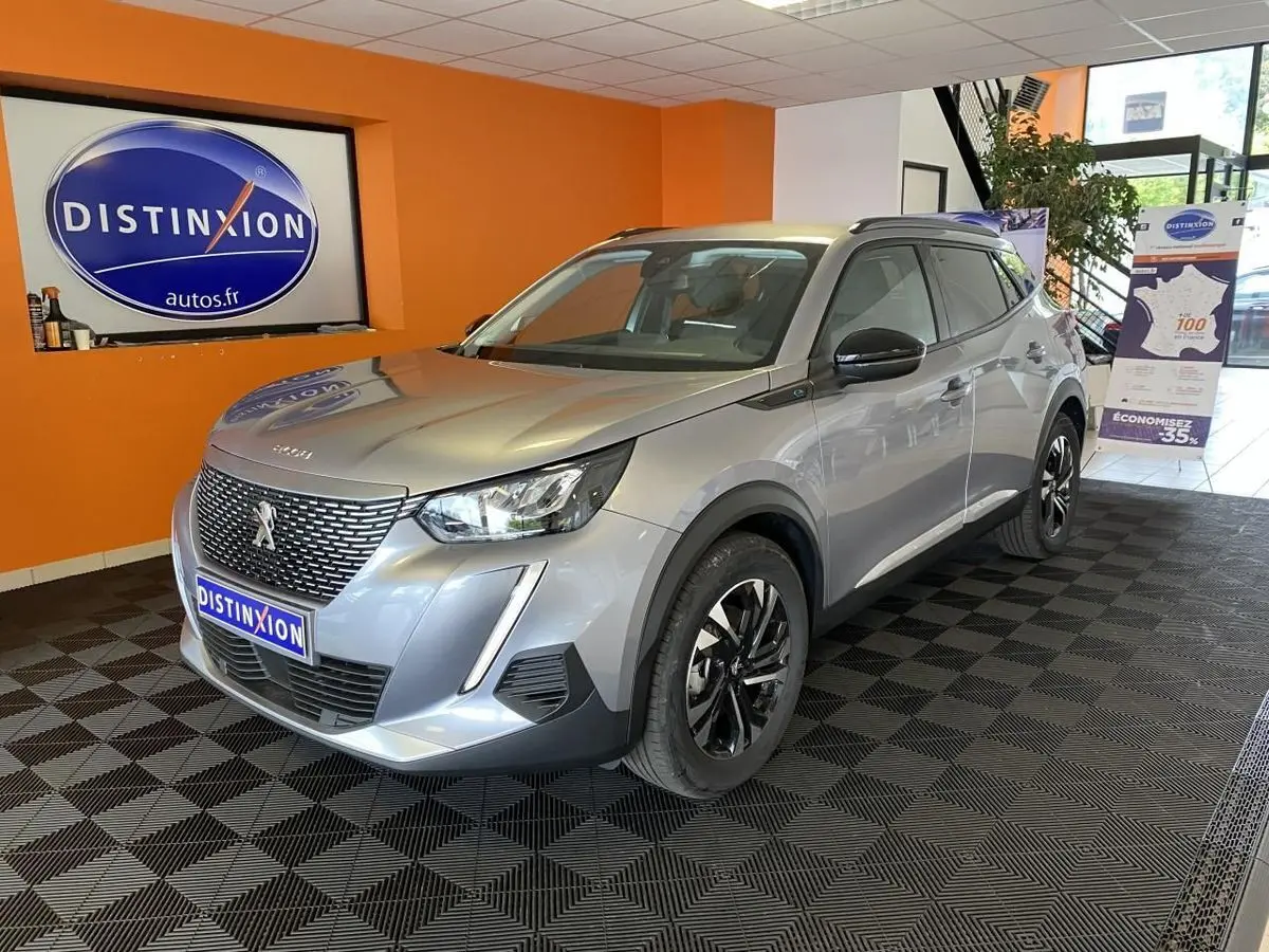 Peugeot 2008 e-136 Allure Pack gris Artense vue 3/4 avant droit en showroom avec jantes bi-tons distinctives.