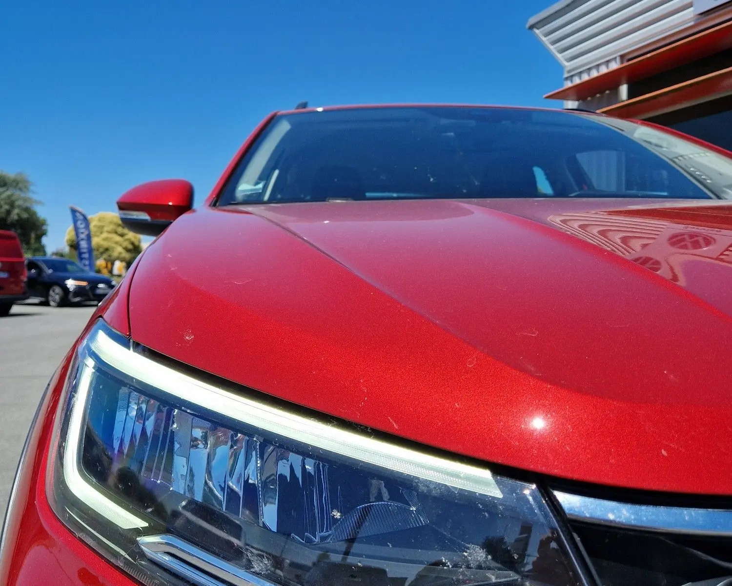 Gros plan sur le phare avant gauche du Volkswagen Taigo rouge roi 2023, soulignant ses lignes modernes et sa calandre chromée.