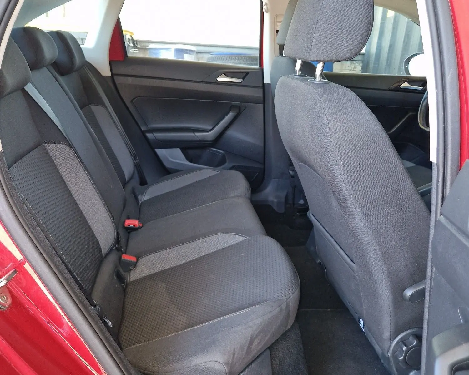 Vue intérieure côté gauche des sièges arrière en tissu gris d'un Volkswagen Taigo rouge roi 2023, porte ouverte.