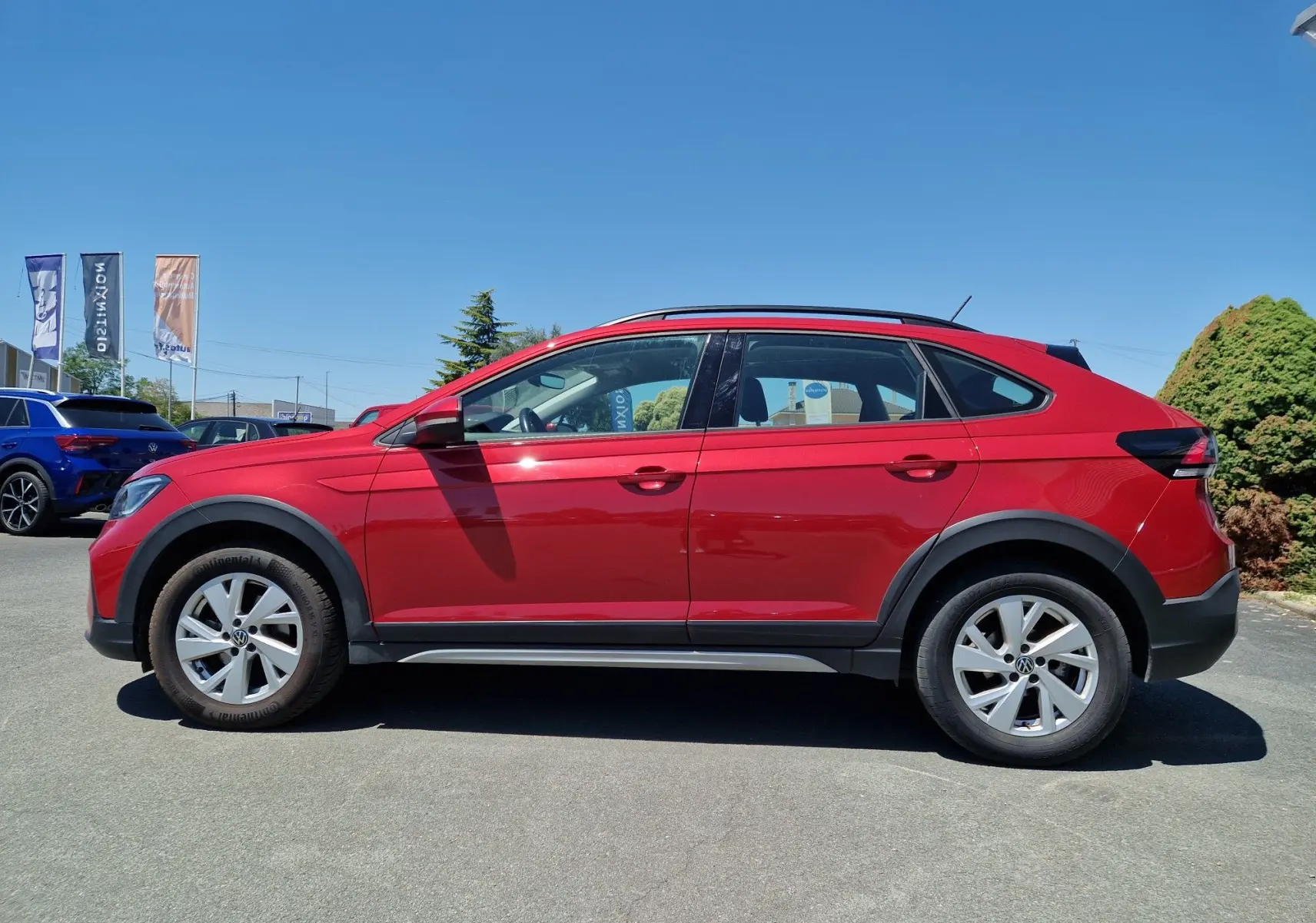 Profil côté gauche d'un Volkswagen Taigo rouge roi 2023, mettant en valeur ses lignes fluides et ses jantes alliage.