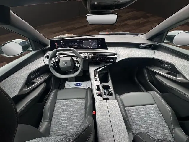 Vue intérieure avant du Peugeot 3008 gris titane 2025, tableau de bord moderne avec écran tactile et volant multifonction.