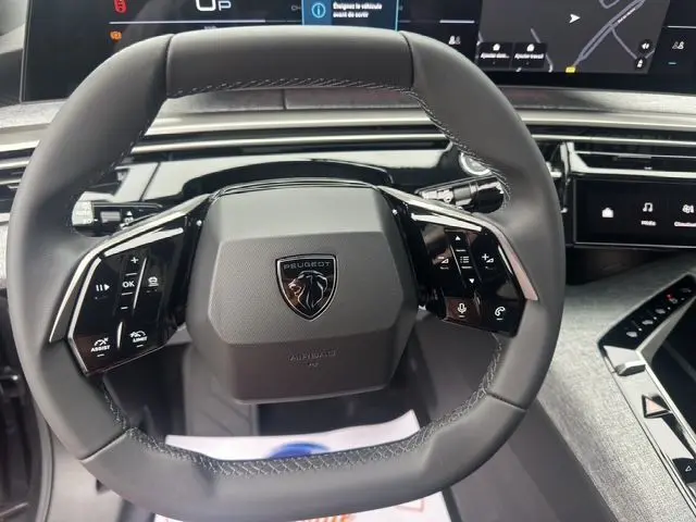Volant multifonction noir de Peugeot 3008 2025 avec logo lion, entouré d'un tableau de bord numérique moderne.