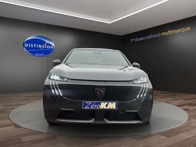 Vue frontale d'un Peugeot 3008 gris titane 2025 avec phares LED et calandre noire distinctive en showroom.