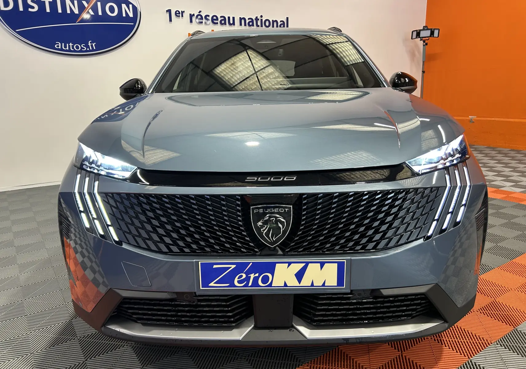 Vue frontale du Peugeot 5008 III Hybrid 145 GT bleu Ingaro avec phares LED allumés et calandre noire texturée.