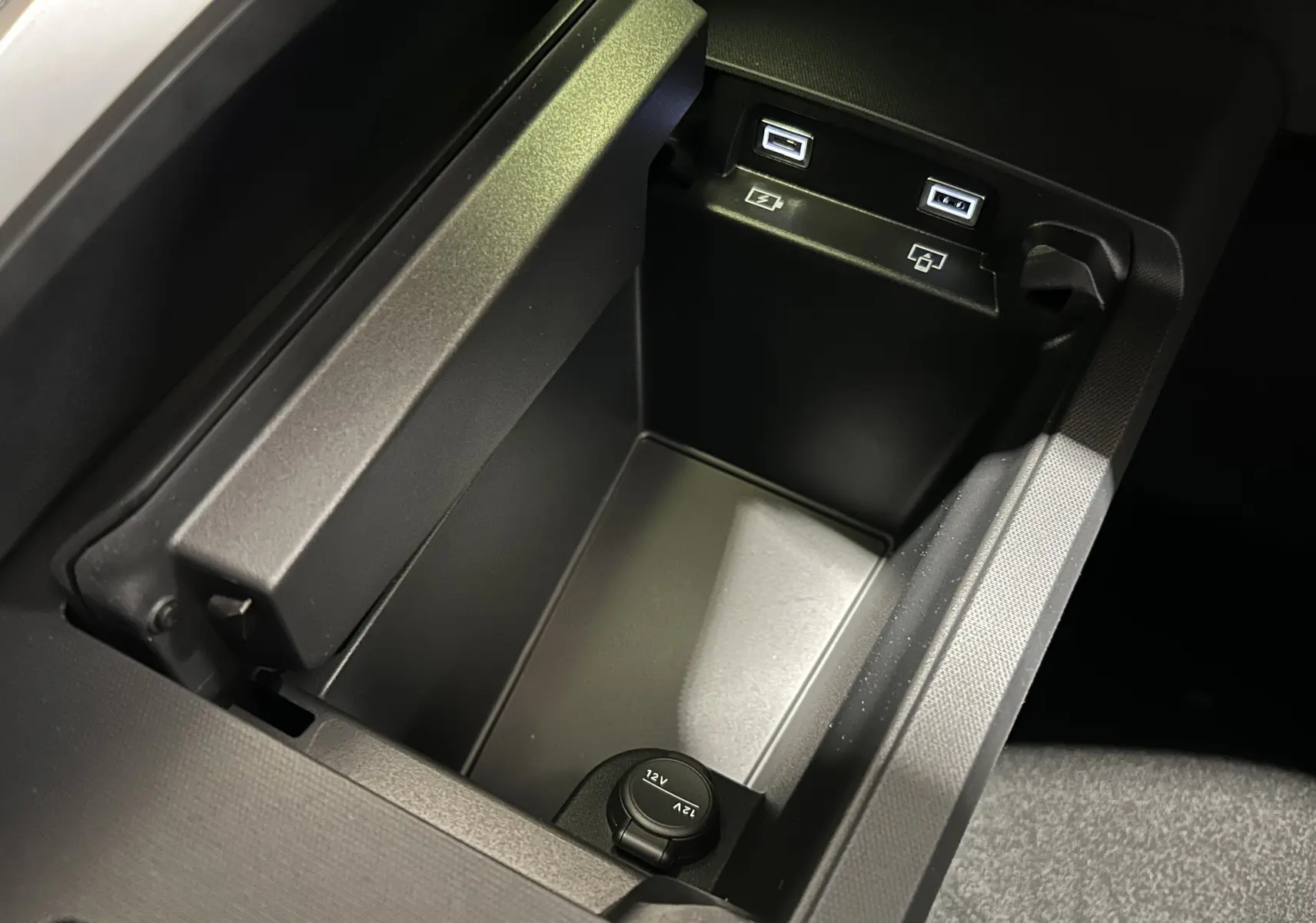 Vue rapprochée de la console centrale noire du Peugeot 5008 III Hybrid avec ports USB et prise 12V intégrés.