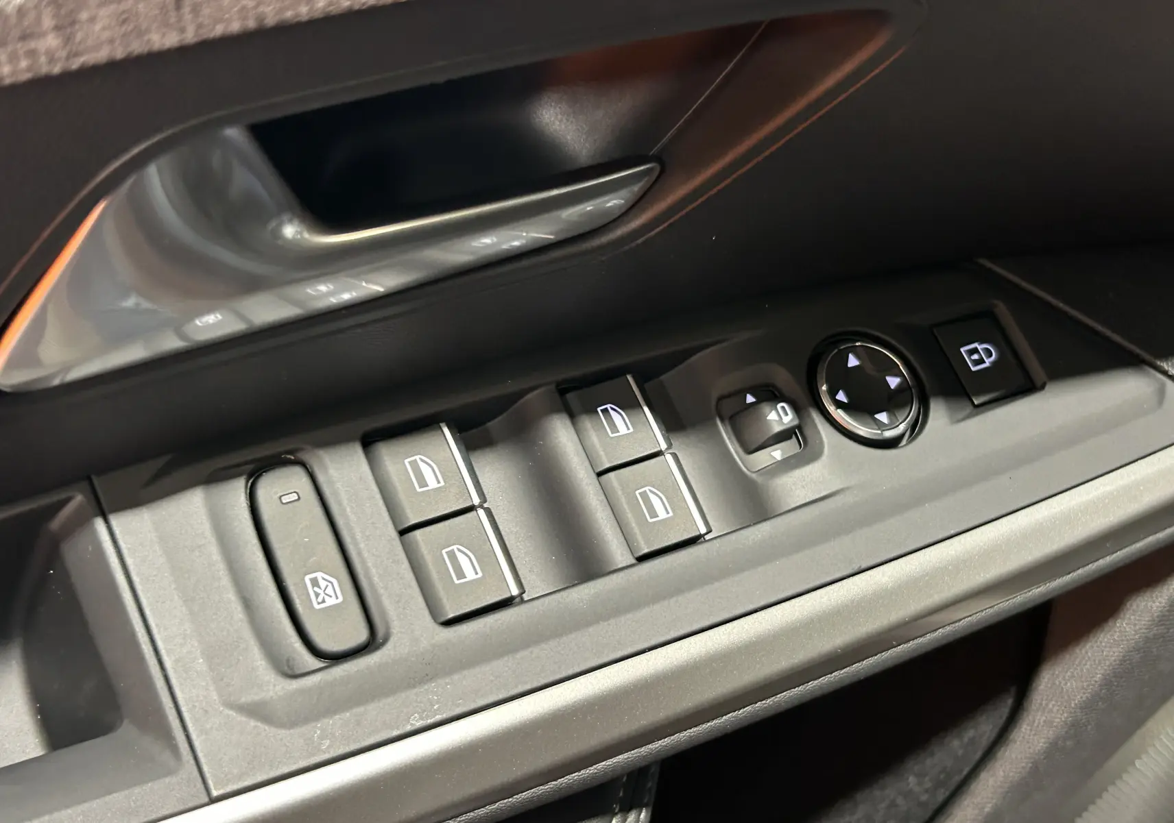 Gros plan sur les commandes des vitres et rétroviseurs côté conducteur du Peugeot 5008 III Hybrid 145 GT, intérieur noir.