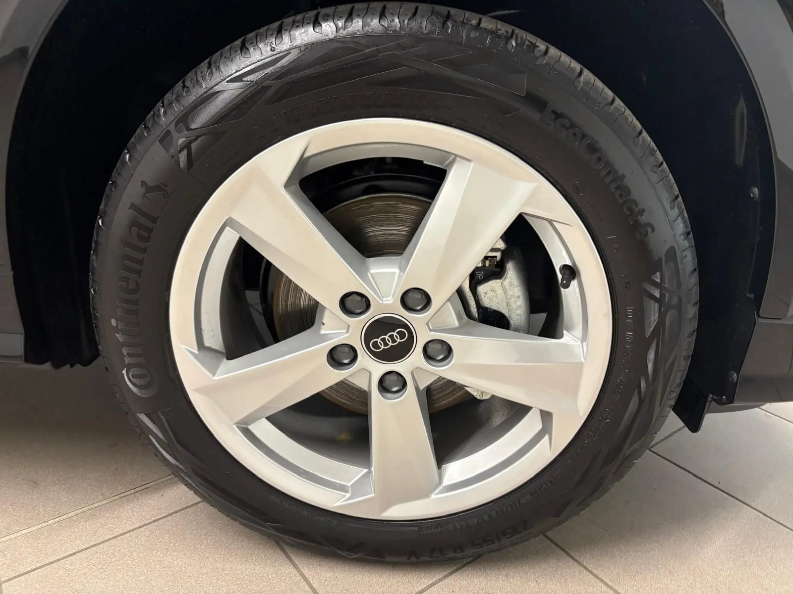 Gros plan sur la roue avant droite d’un Audi Q2 Noir Mythic avec jante alliage 5 branches et pneu Continental.