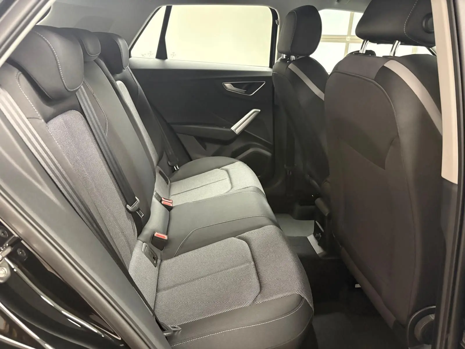Vue intérieure du côté gauche des sièges arrière de l'Audi Q2 35 TFSI S Line 2026 en tissu gris et noir.