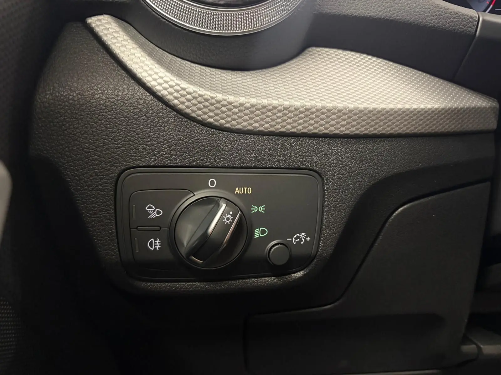 Gros plan sur le panneau de commande des phares à gauche du volant dans l’Audi Q2 35 TFSI 150 S Line noir Mythic.