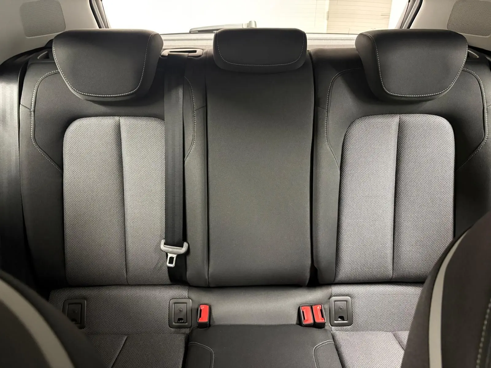Vue arrière des sièges arrière en tissu gris et noir de l’Audi Q2 35 TFSI S Line 2026, avec ceinture de sécurité centrale visible.