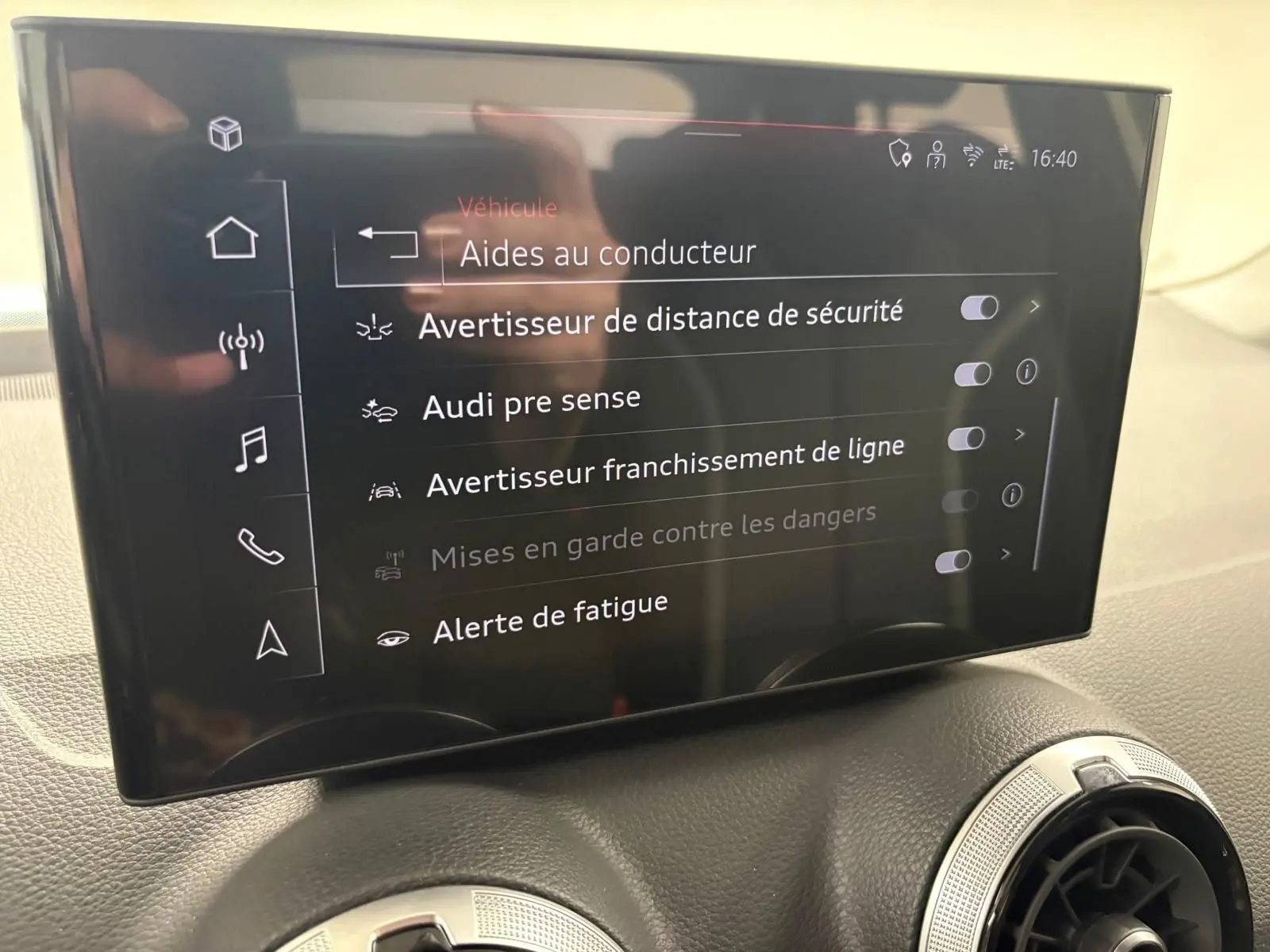Écran tactile intérieur de l'Audi Q2 35 TFSI S Line affichant les aides à la conduite, vue rapprochée du tableau de bord.