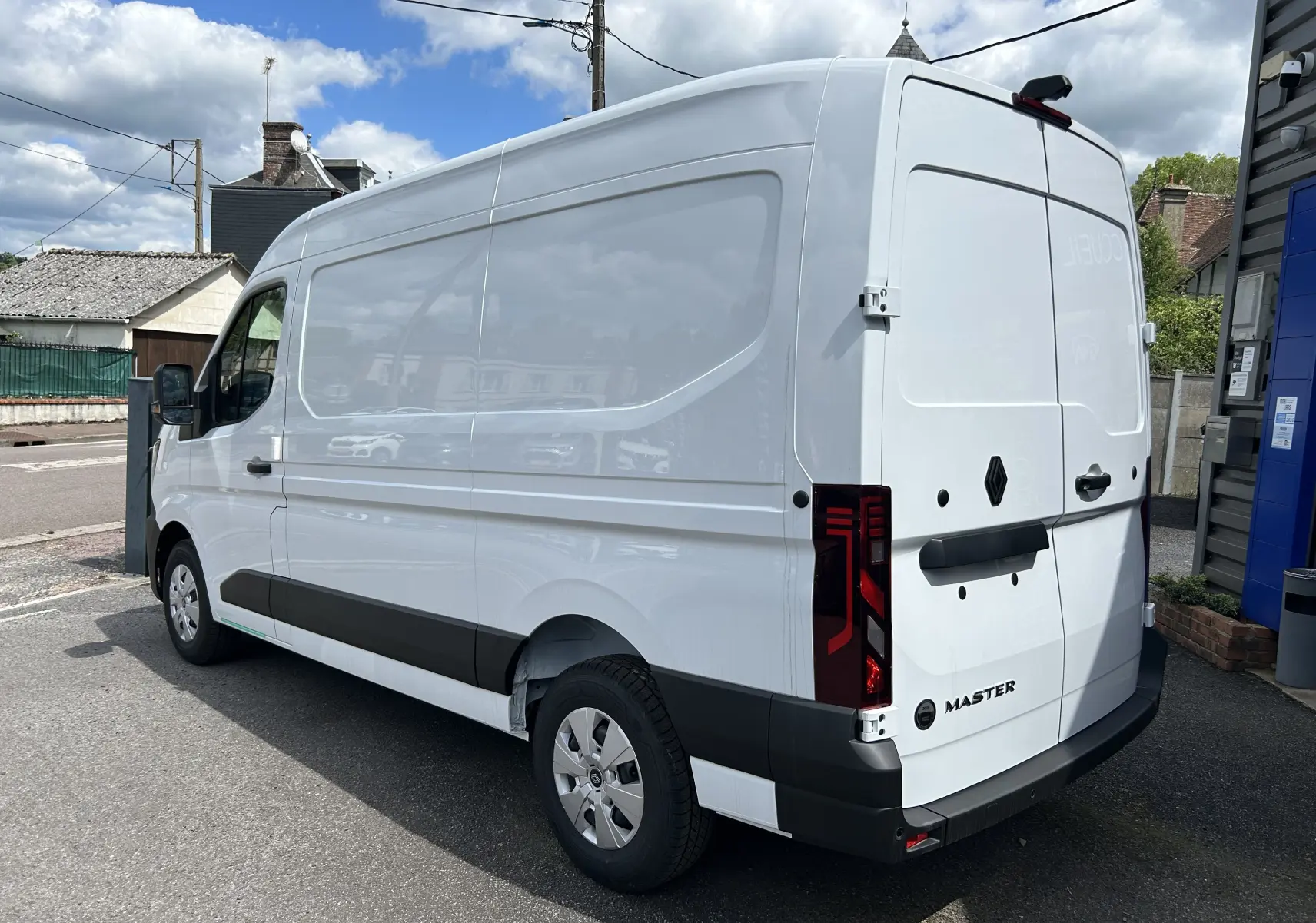 Vue 3/4 arrière droite d’un Renault Master blanc, fourgon utilitaire avec feux arrière verticaux et logo noir.