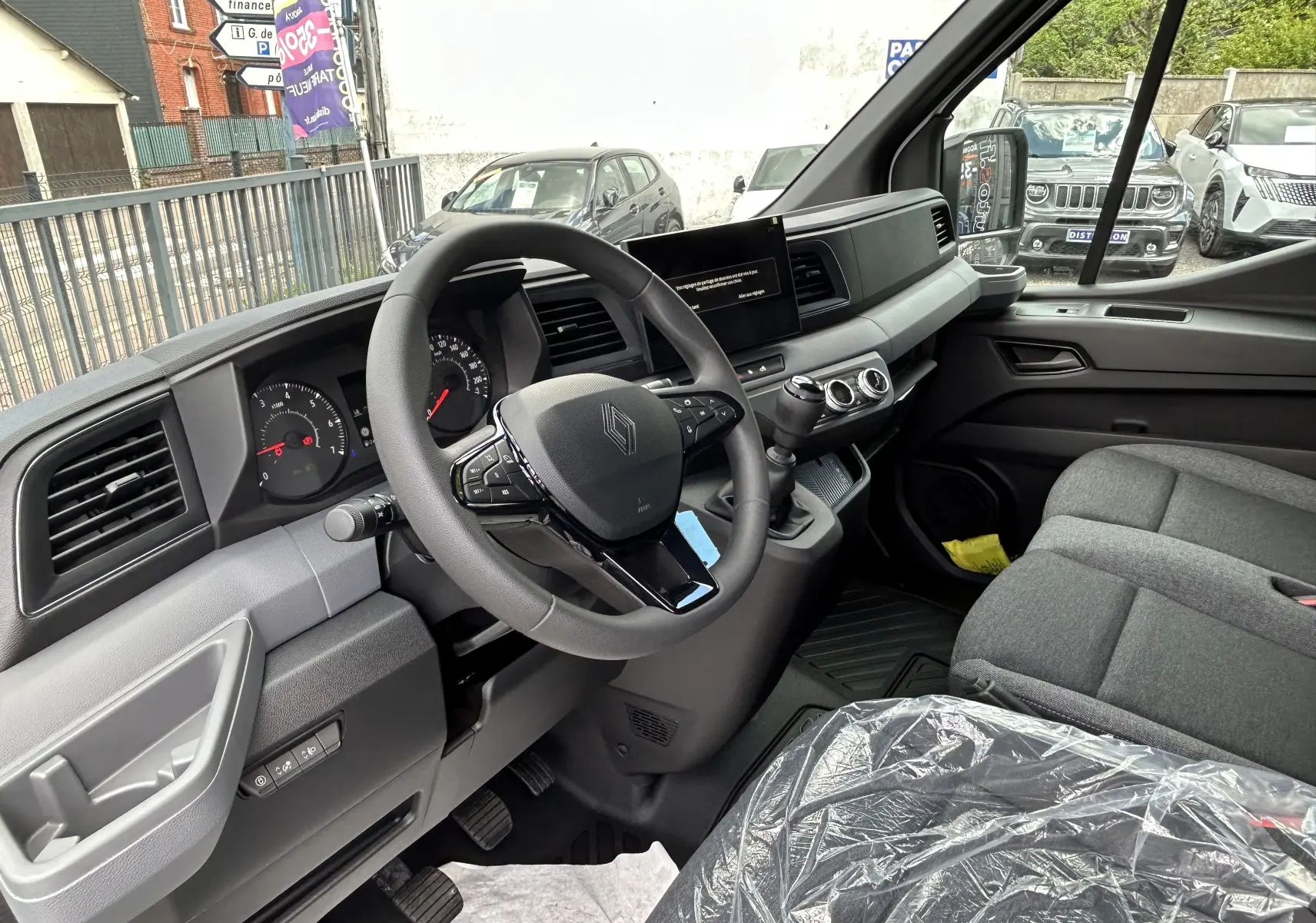 Vue intérieure côté conducteur du Renault Master 2025, tableau de bord moderne avec volant multifonction et sièges gris tissu.