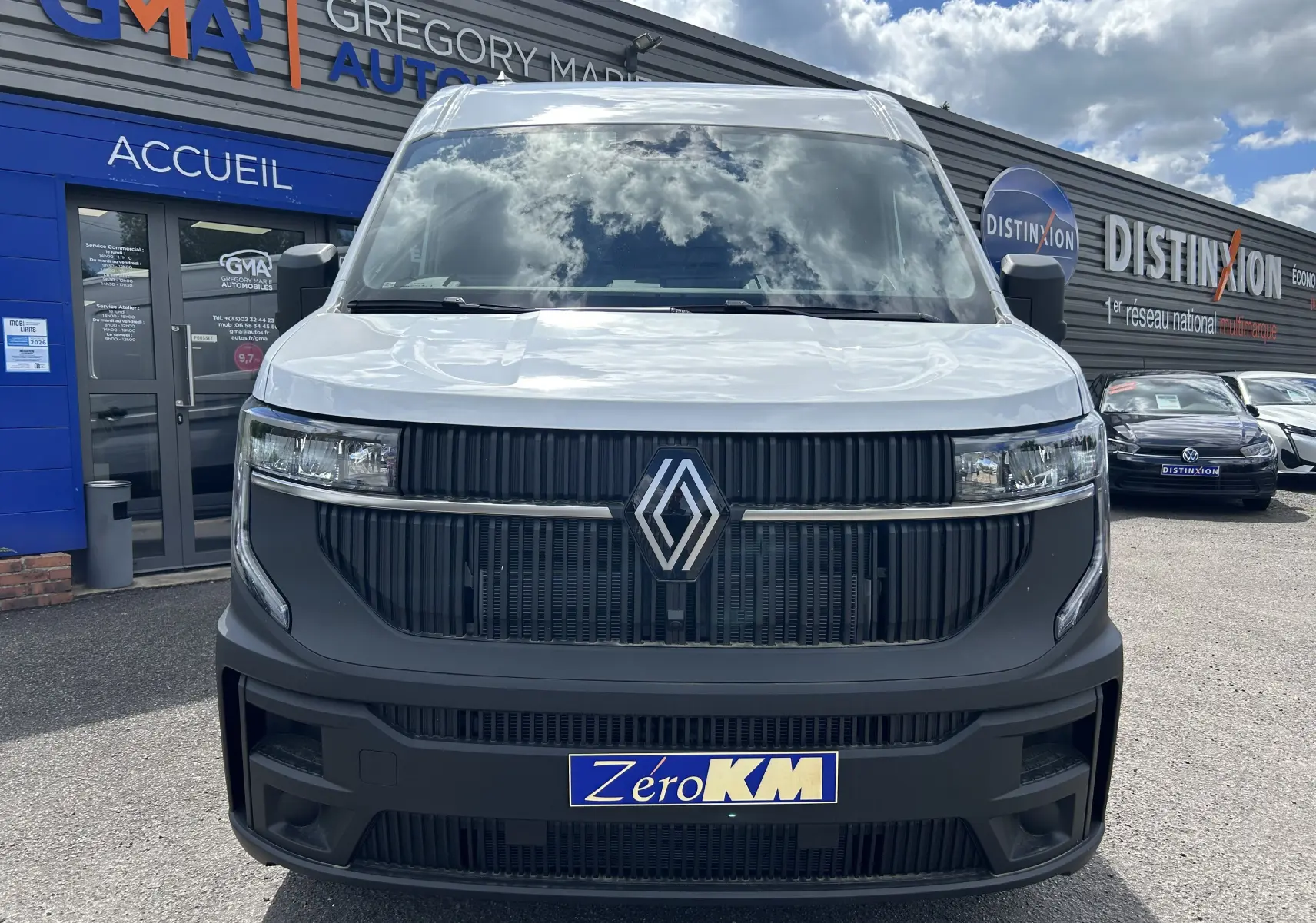 Vue frontale d’un Renault Master blanc 2025 avec calandre noire et logo Renault bien visible, stationné devant un garage.