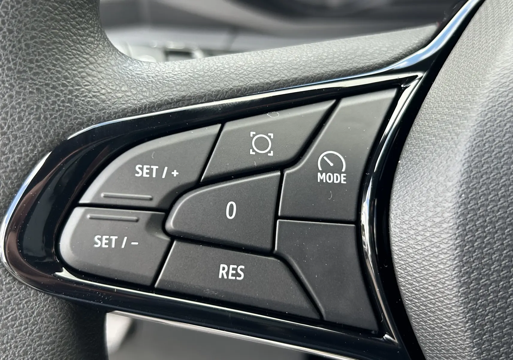 Gros plan sur les commandes noires du volant du Renault Master 2025, avec boutons de réglage de vitesse et mode.