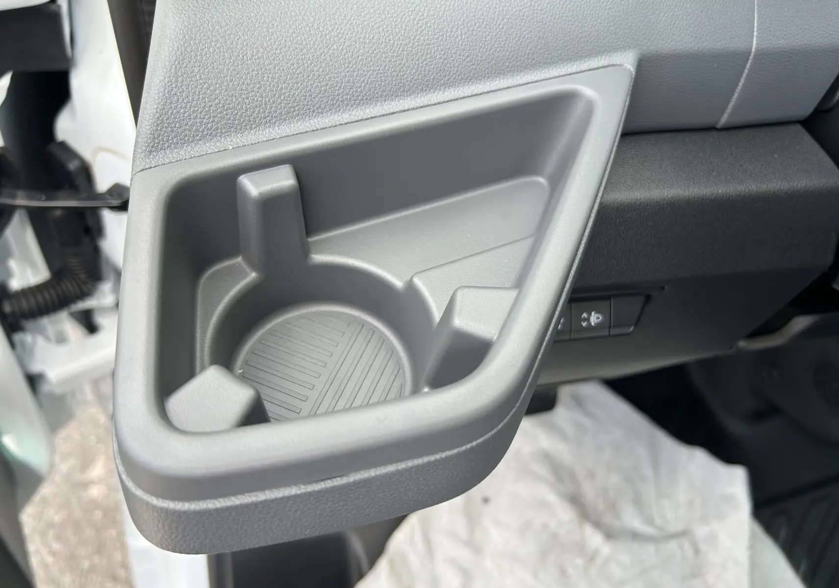 Gros plan sur le porte-gobelet gris intégré côté conducteur du Renault Master blanc, intérieur avant droit visible.