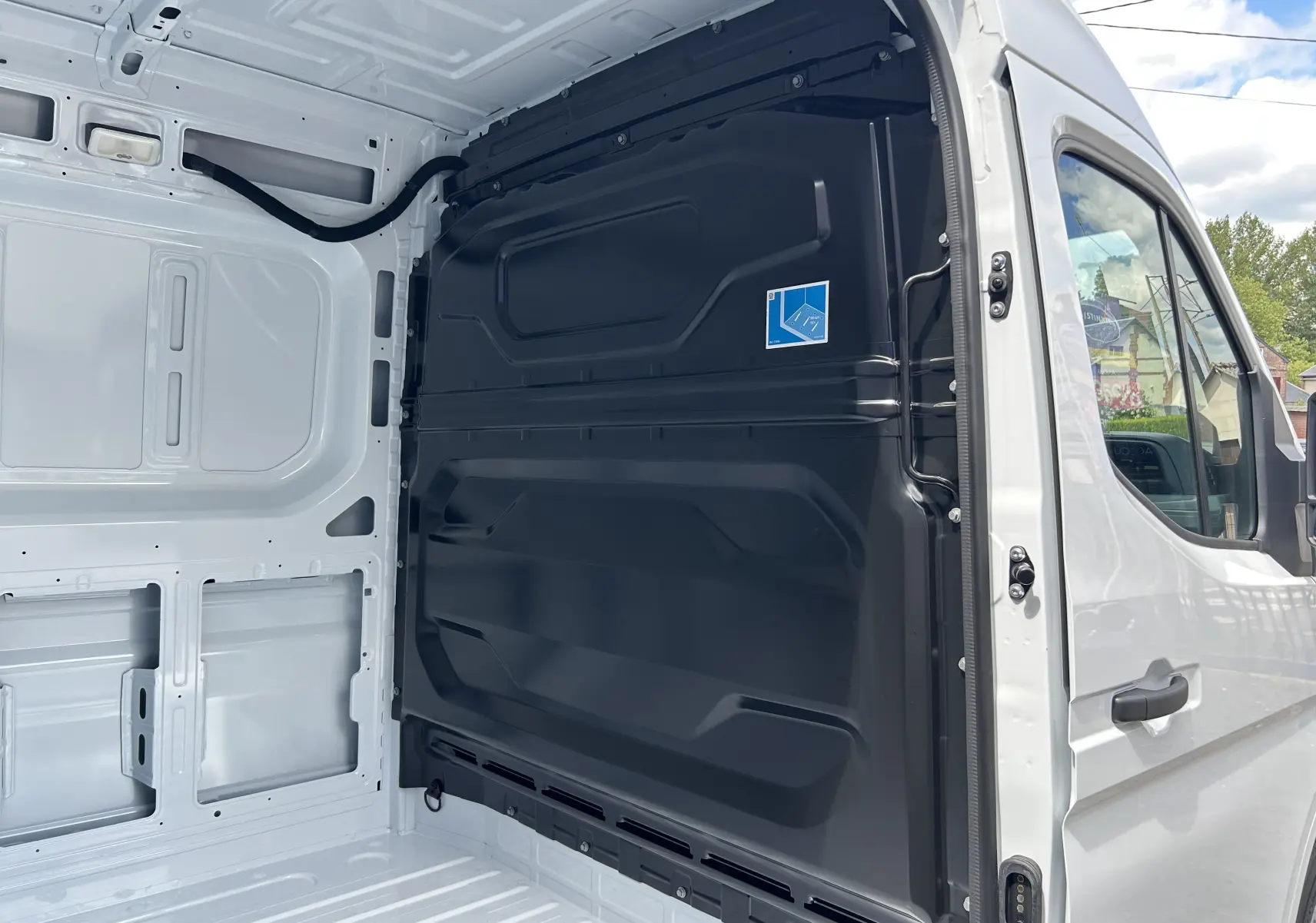 Vue intérieure côté droit du fourgon blanc Renault Master 2025, montrant la cloison noire séparant la cabine et la zone de chargement.