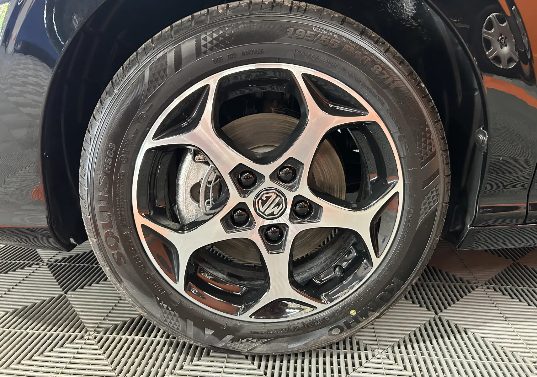 Gros plan sur la roue avant droite du MG3 Hybrid+ 195 Luxury Pebble Black avec jante alliage bicolore et logo MG central.