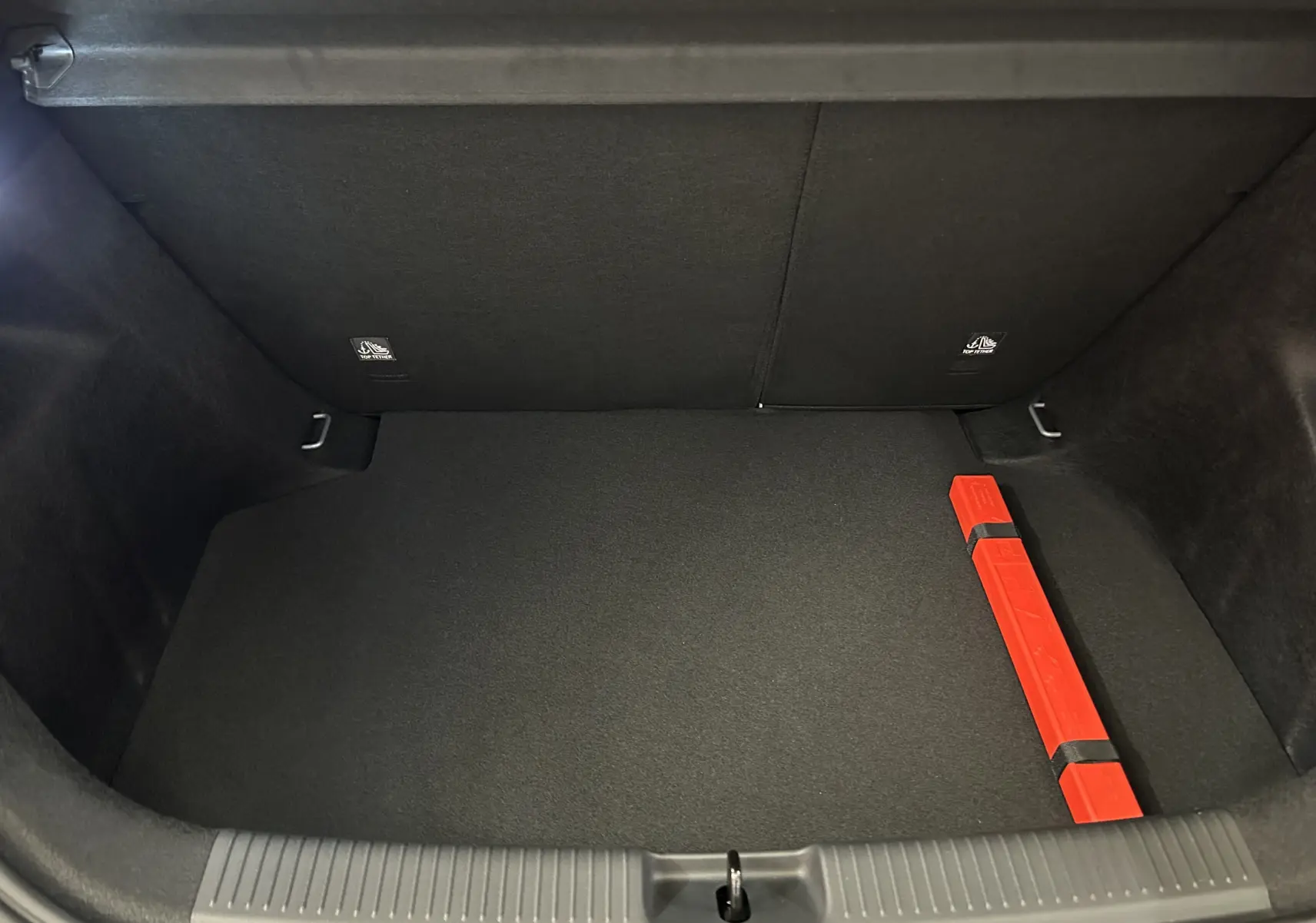Coffre ouvert de MG3 Hybrid+ 195 Luxury Pebble Black, vue intérieure avec tapis noir et triangle de signalisation rouge.