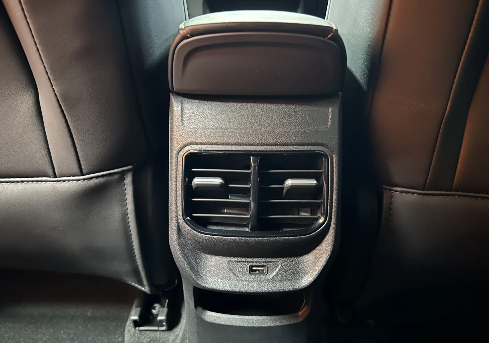 Détail de la console arrière avec bouches d’aération et port USB du MG3 Hybrid+ 195 Luxury Pebble Black 2026.