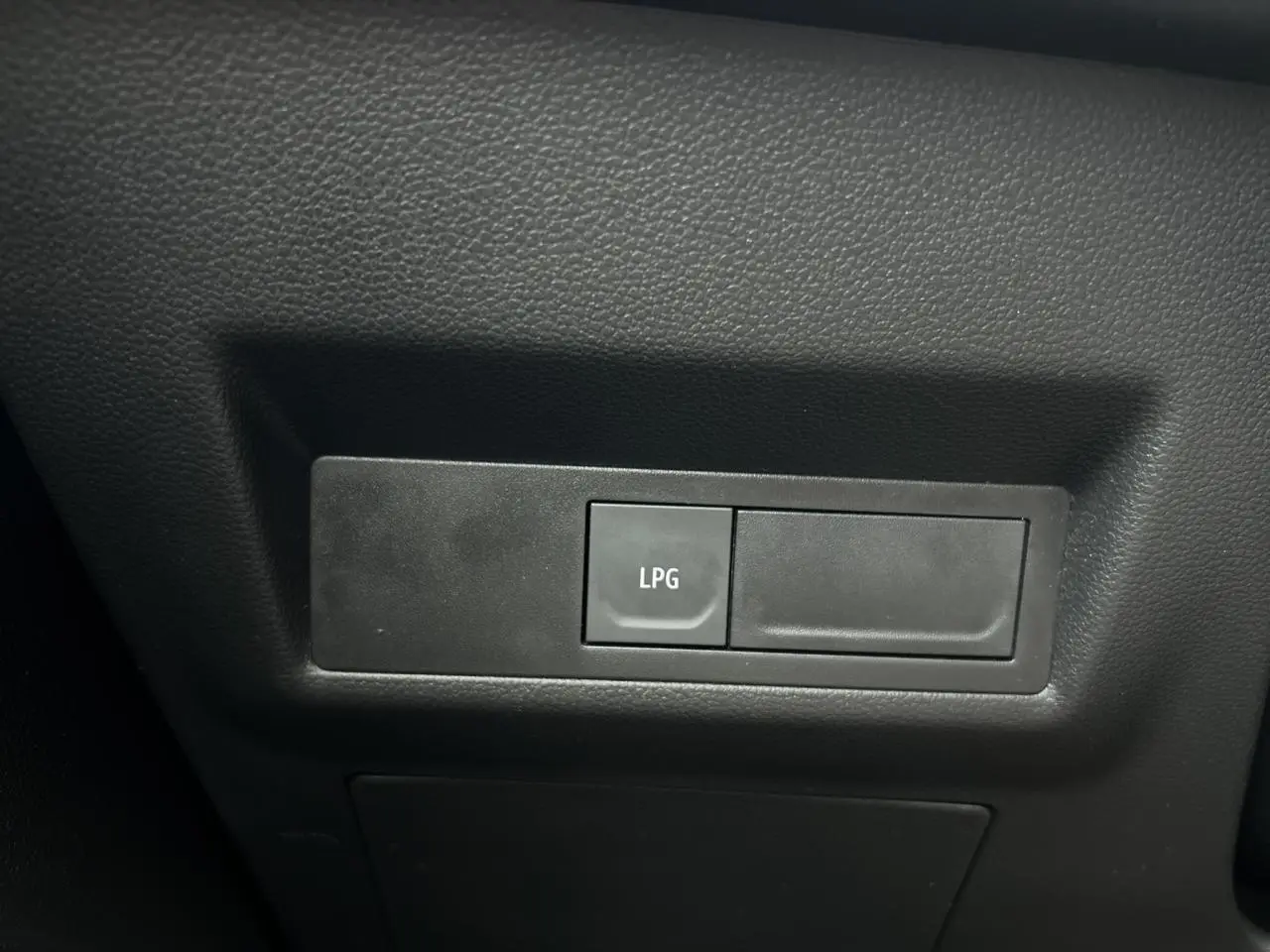 Bouton de commande LPG en gros plan sur le tableau de bord intérieur noir du Renault Captur 2025.