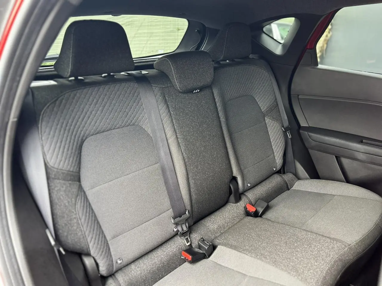 Vue intérieure sur les sièges arrière gris du Renault Captur 2025, avec ceintures et appuie-têtes visibles.