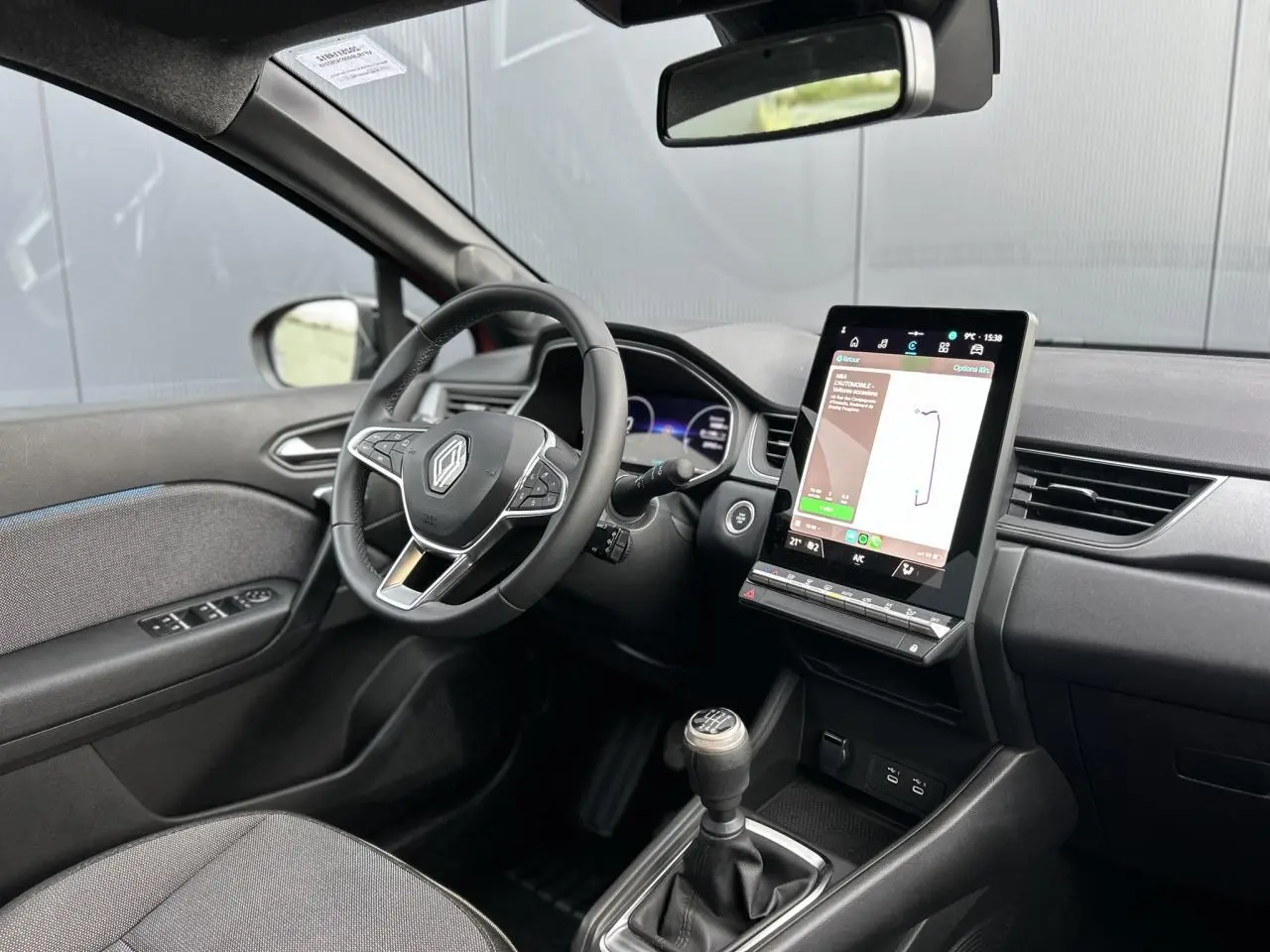 Intérieur Renault Captur 2025 vu côté conducteur, tableau de bord noir avec écran tactile vertical et boîte manuelle.