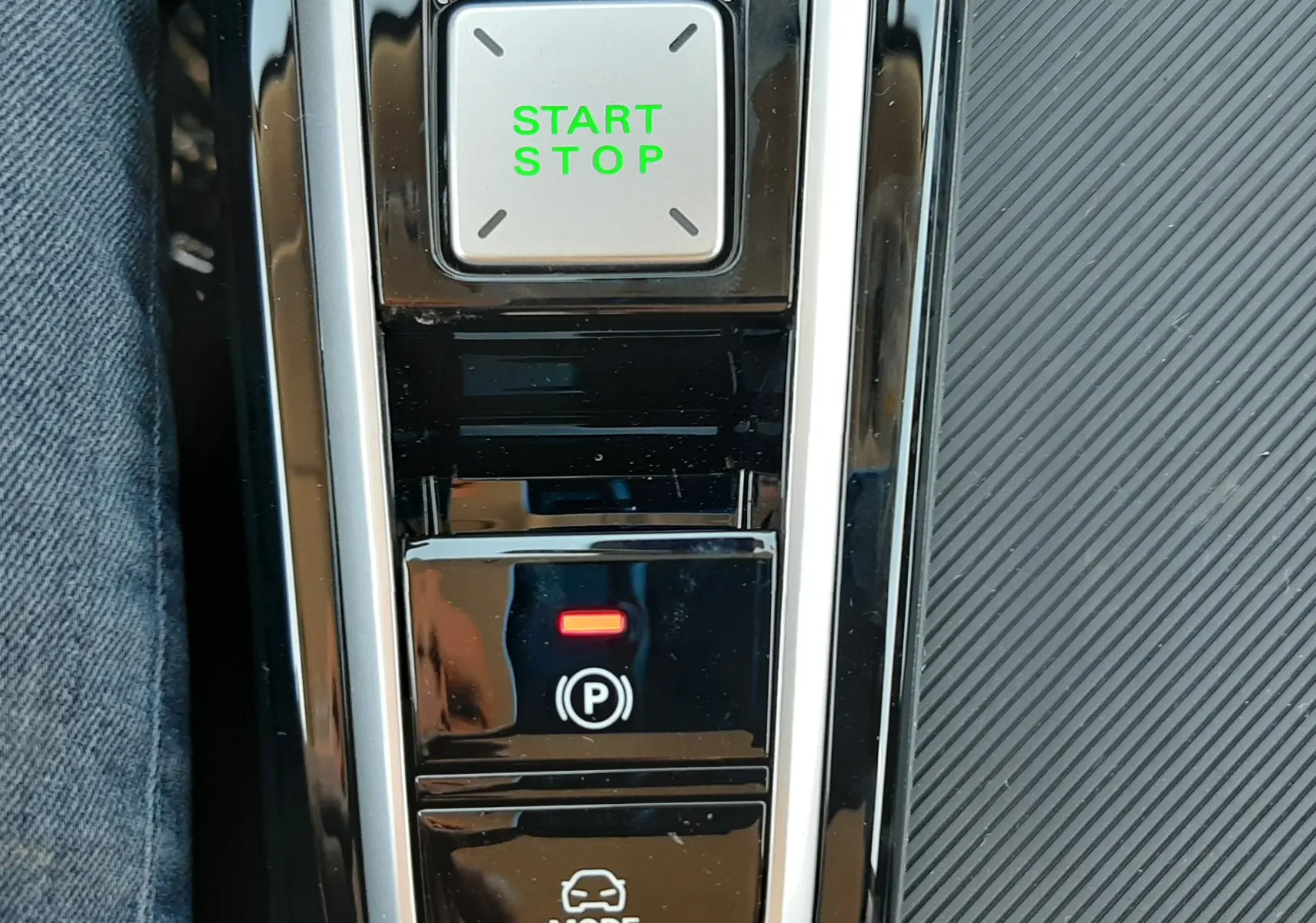 Gros plan sur la console centrale noire brillante du MG ZS Emerald Green, montrant les boutons Start Stop, frein à main et mode de conduite.