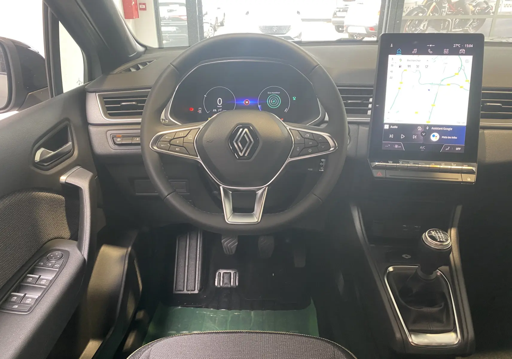 Vue intérieure du poste de conduite du Renault Captur II gris zinc, avec volant multifonction, écran tactile vertical et levier de vitesse manuel.