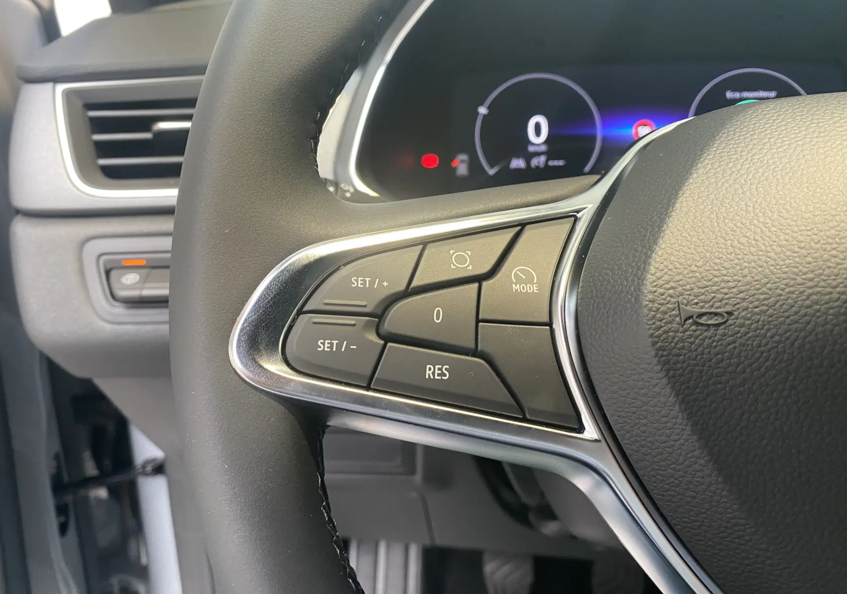 Gros plan sur la partie gauche du volant du Renault Captur II 2024, avec commandes de régulateur et tableau de bord numérique.