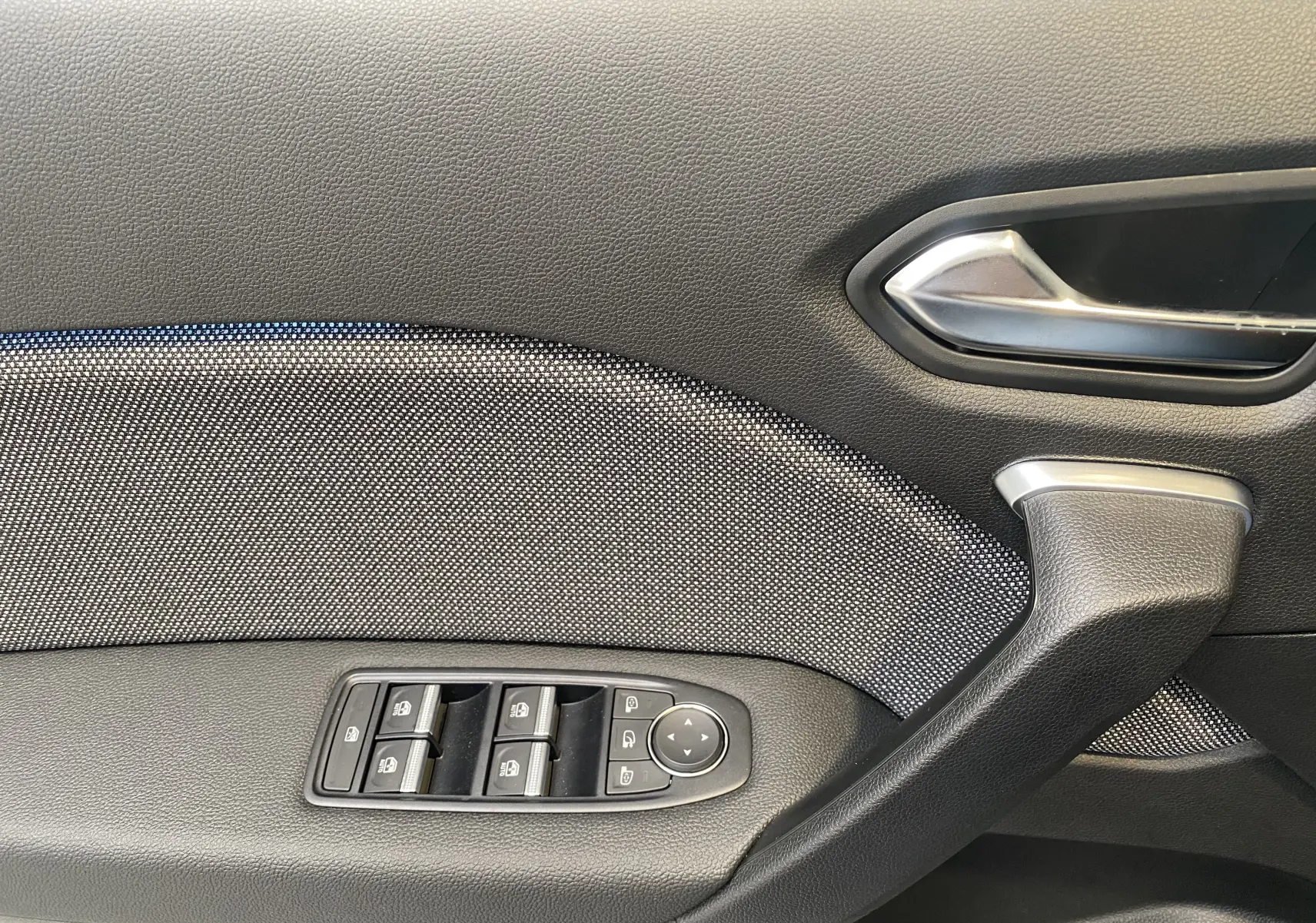 Gros plan sur la portière côté gauche du Renault Captur gris zinc métal, montrant les commandes des vitres et la poignée intérieure.