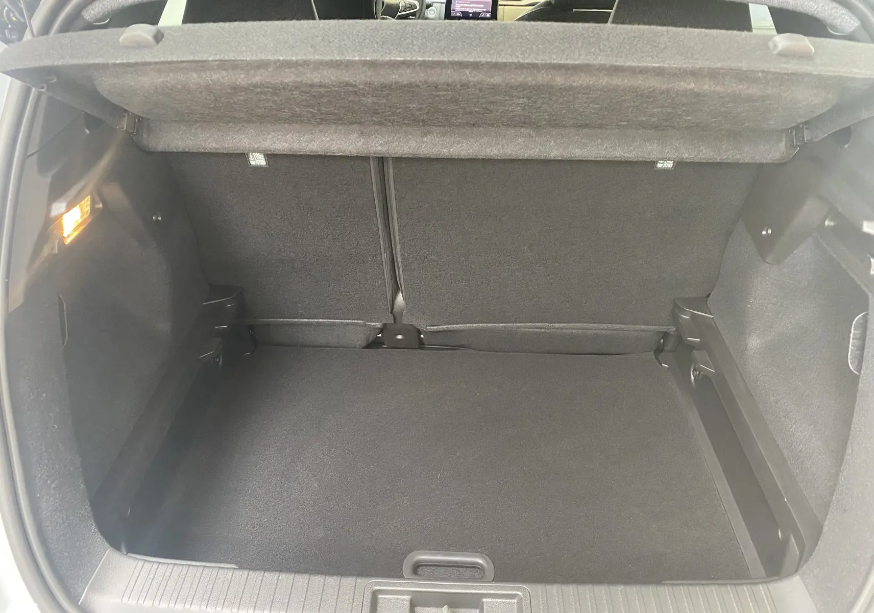 Coffre ouvert du Renault Captur II gris zinc métal, vue intérieure arrière montrant l'espace de chargement vide et la tablette cache-bagages.