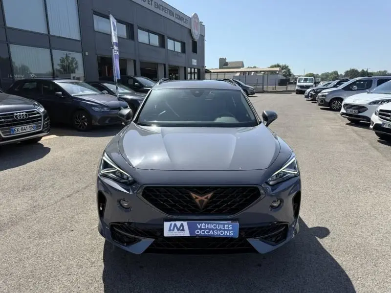 Vue frontale d'un CUPRA Formentor gris 2023 avec calandre noire et logo cuivré, stationné en extérieur.