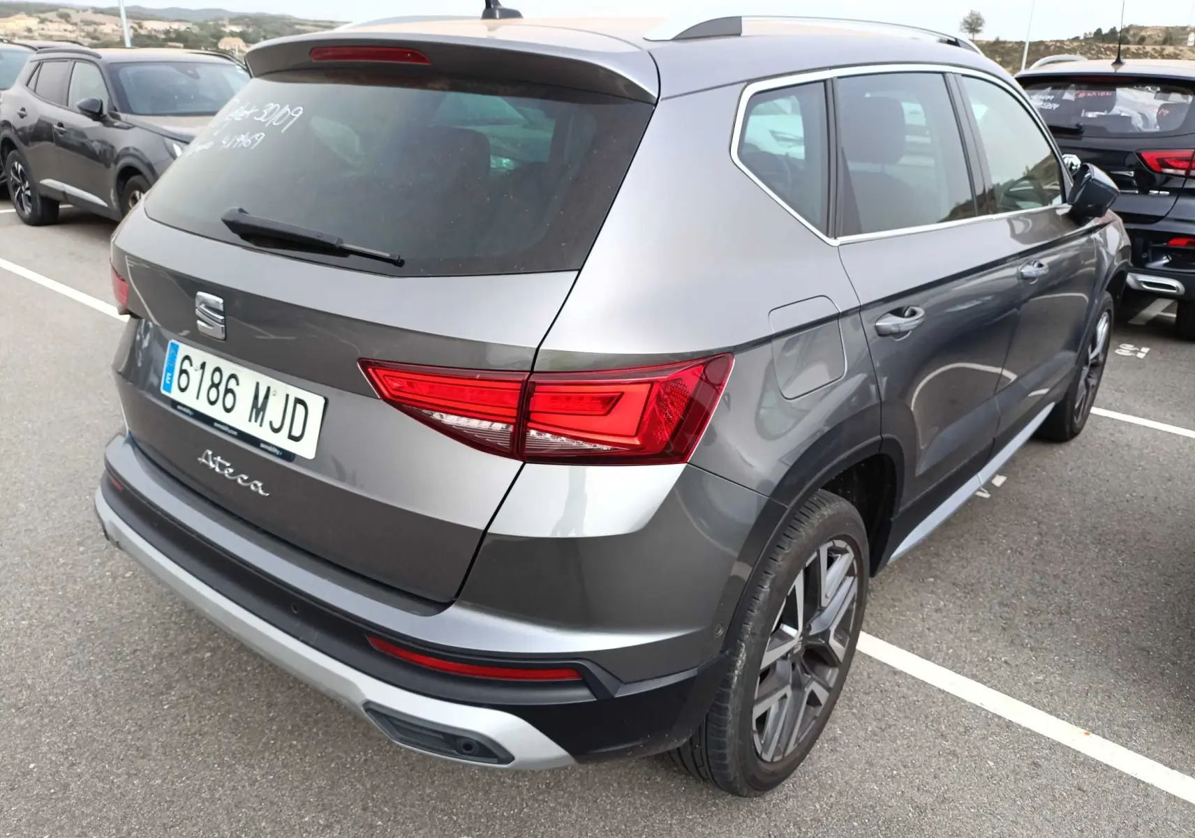 Vue 3/4 arrière droite d'un SEAT Ateca gris foncé métal 2023 avec feux arrière LED et jantes alliage.