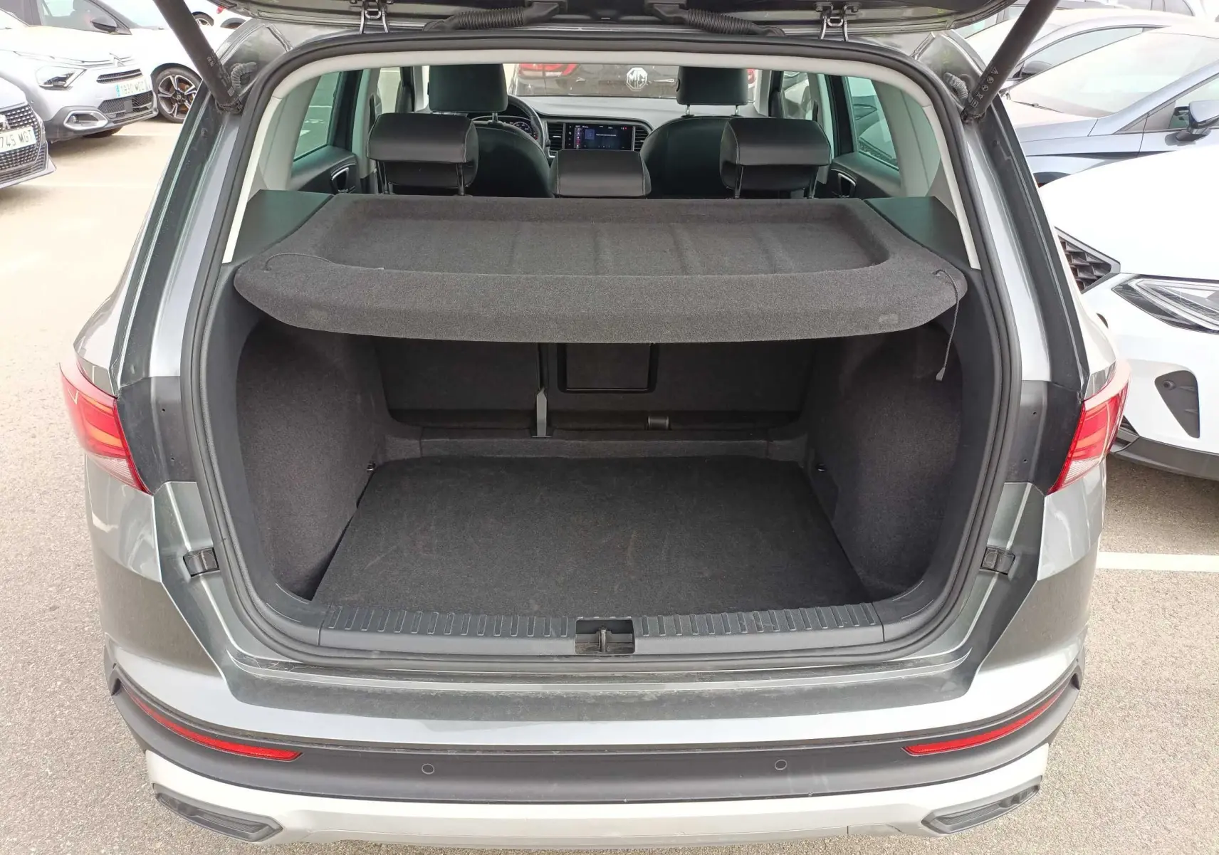 Vue arrière ouverte du coffre d’un SEAT Ateca gris foncé métal 2023, montrant l’espace de chargement et la plage arrière.