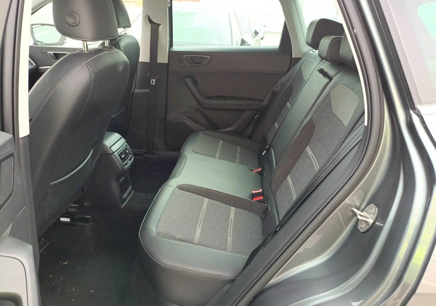 Vue côté droit de l’habitacle arrière du SEAT Ateca gris foncé, montrant les sièges bi-matière et les aérations centrales.
