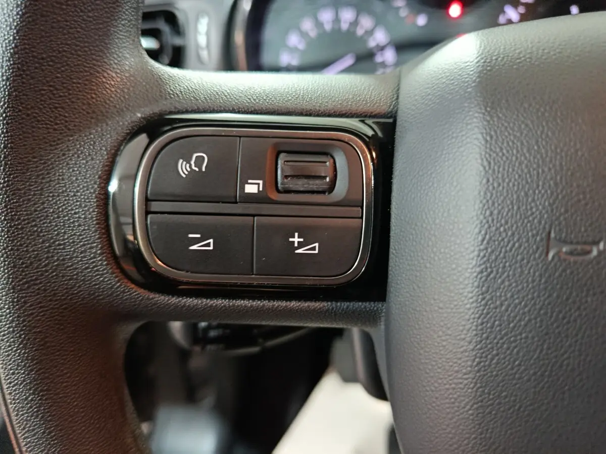 Gros plan sur les boutons de commande du volant noir de la Citroën C3 2024, avec commandes vocales et réglage du volume.