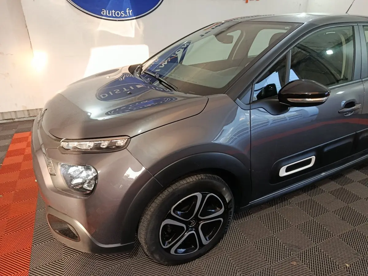 Vue 3/4 avant droit d'une Citroën C3 gris foncé avec phares LED et protections latérales noires.
